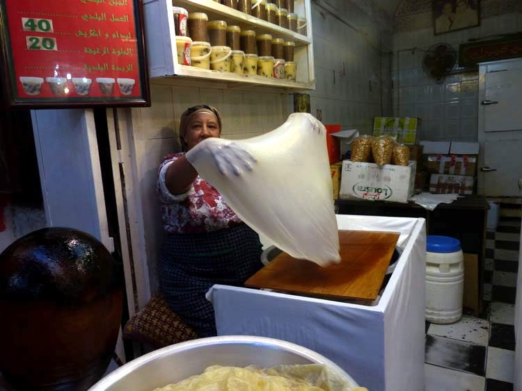 The cook is stretching to dough paper-thin in preparation of cooking.