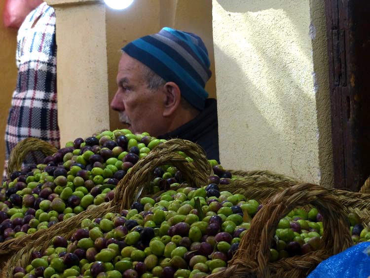 Green and dark olives in large bowls in the market.