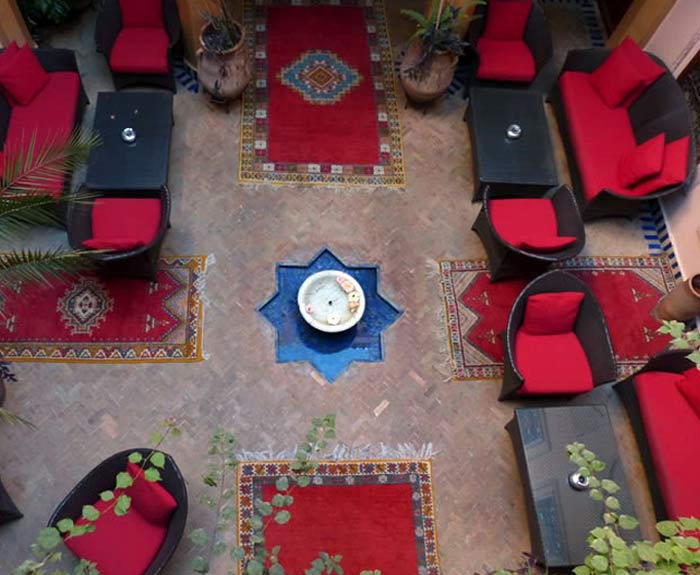 A water fountain surrounded by carpets and red seating.