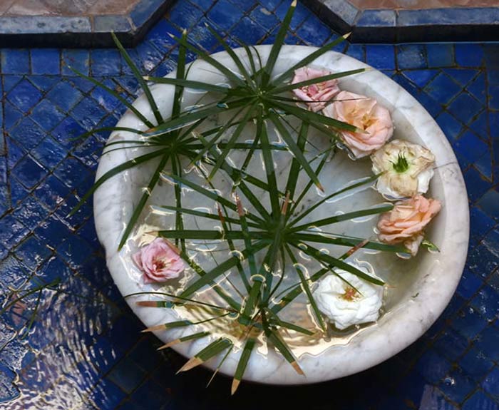 A large fountain basin, with decorative flowers and palm leaves.