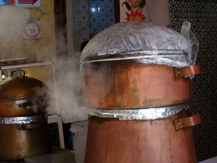 Large, stacked copper kettles in the market.