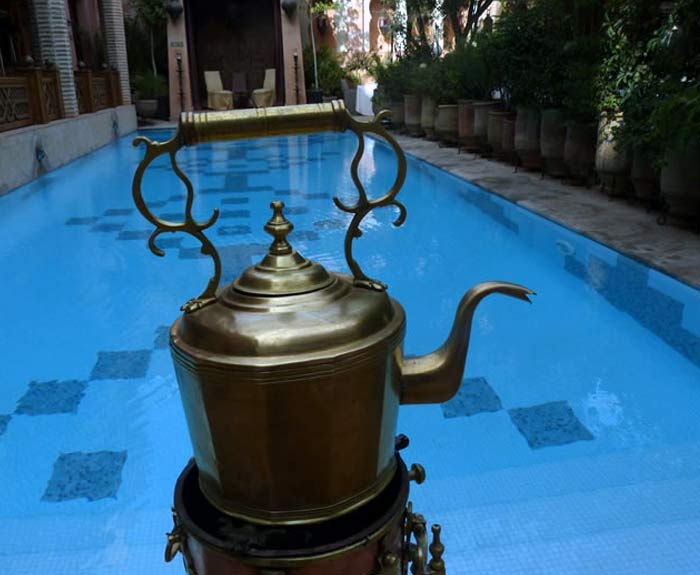 Antique teapot in front of a pool of blue water.