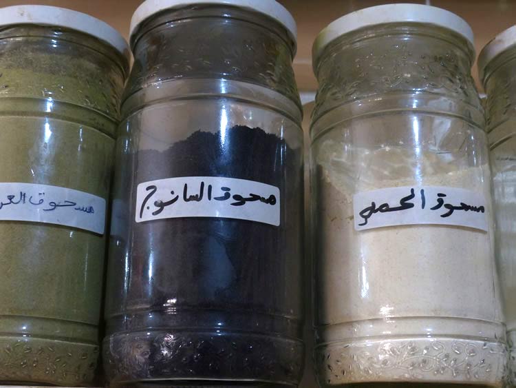 Glass jars of dried spices on a shelf in the market.