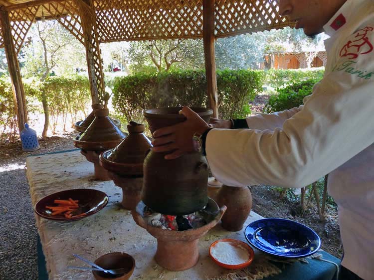 Open air clay cooking with the chef taking the top of the clay cooker.