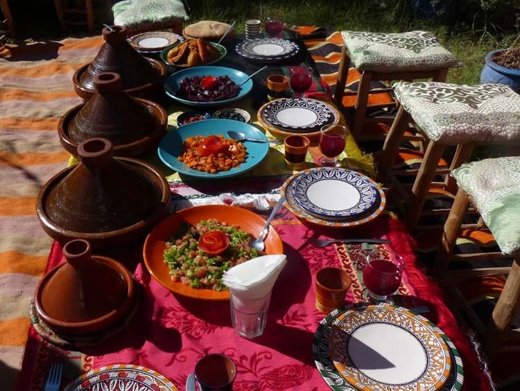 A beautiful table filled with platters of clay cookers and food around the table.