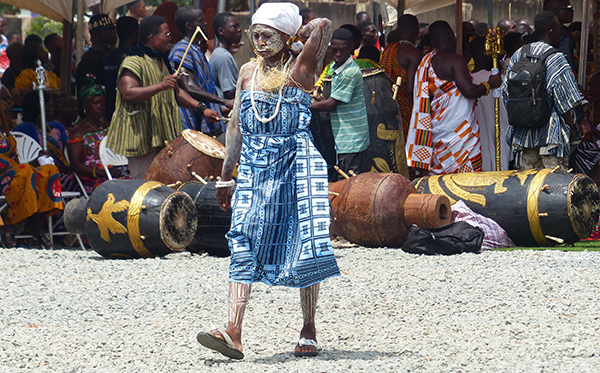 The young dancer dressed in a blue and white dress with a white paste on her face and body.  