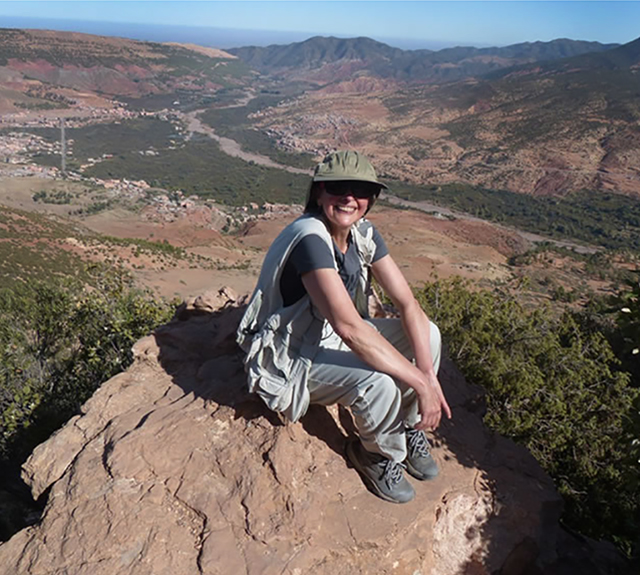 Woman sitting on rock, overlooking the valley.