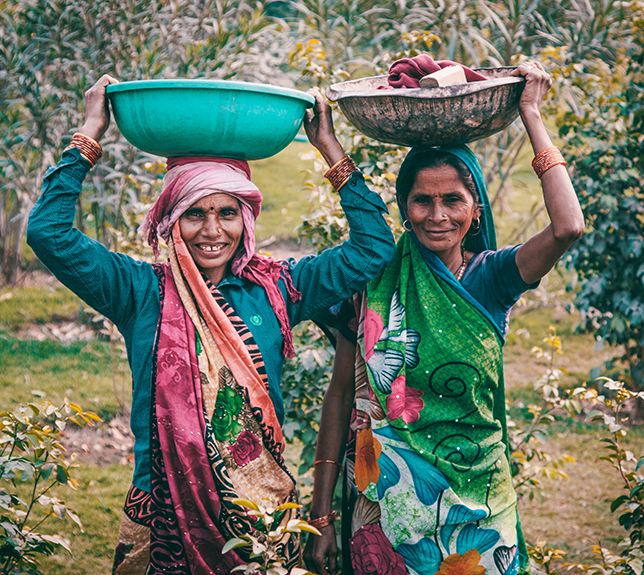 Two indigenous women carrying food in baskets on their heads