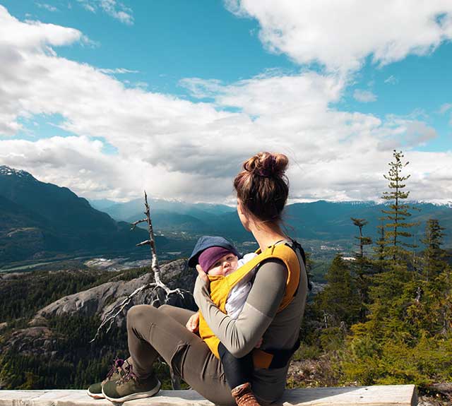 Mother holding baby looking out on the distant mountains