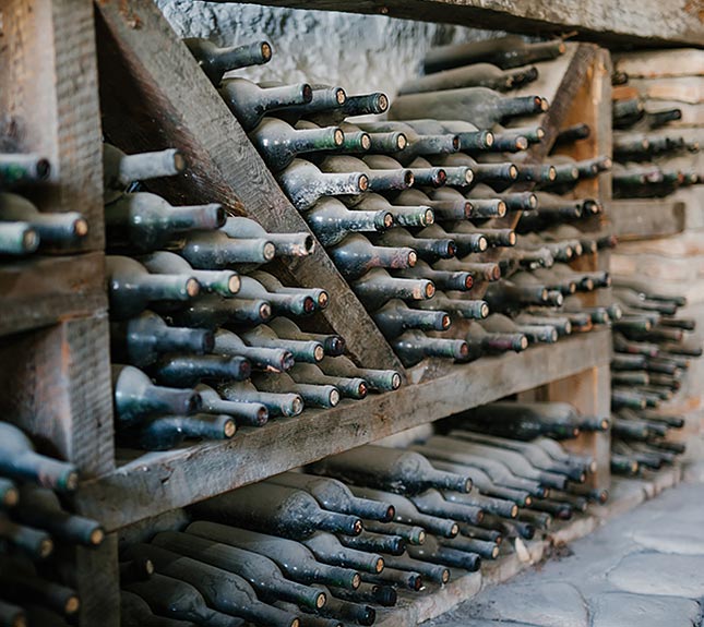 Rows of bottles of wine covered with dust.
                      