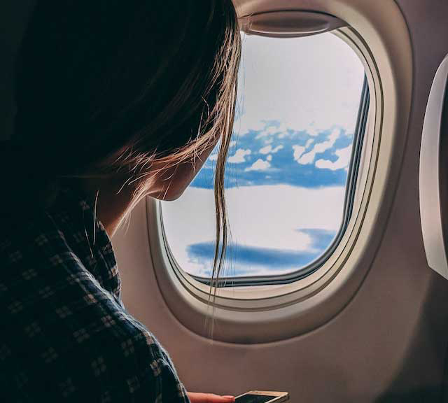 Young woman looking out of window on plane.