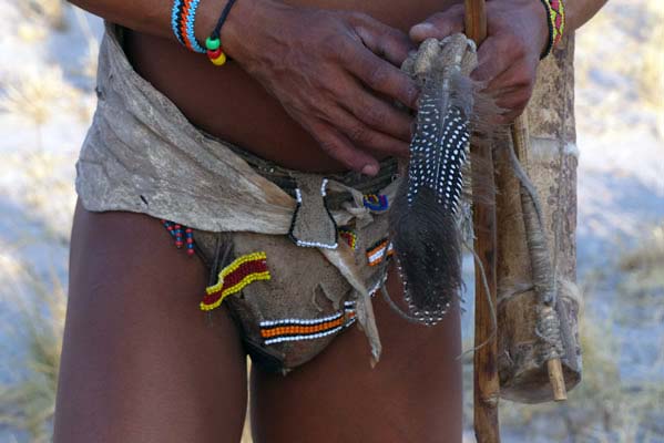 African hunter with a decorative loin cloth, carrying his tools over his shoulders. 