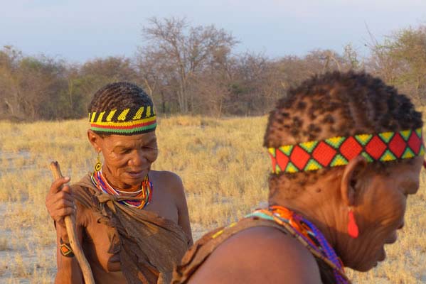 2 African men talking to one another with colorful, beaded headdresses.