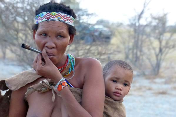 African mother and child on her back, smoking.