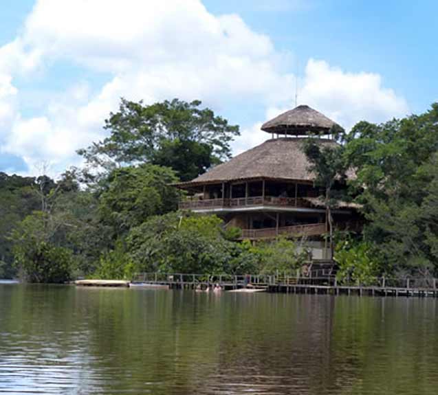 Gray, multi-story building on a river with a dock landing.