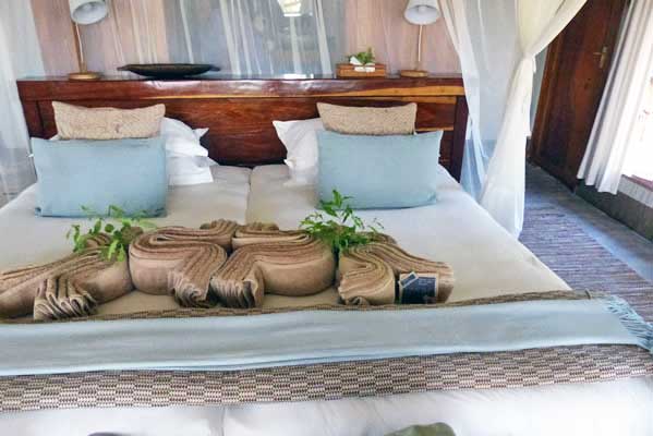 A luxurious camp tent bedroom, with decorative folded towels.