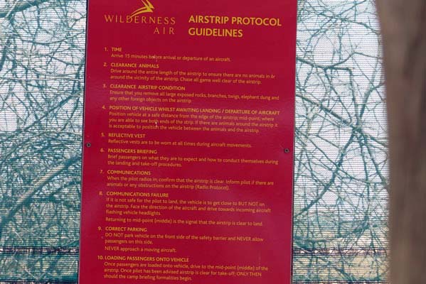 A sign at the landing strip with protocol for landing on the air strip.