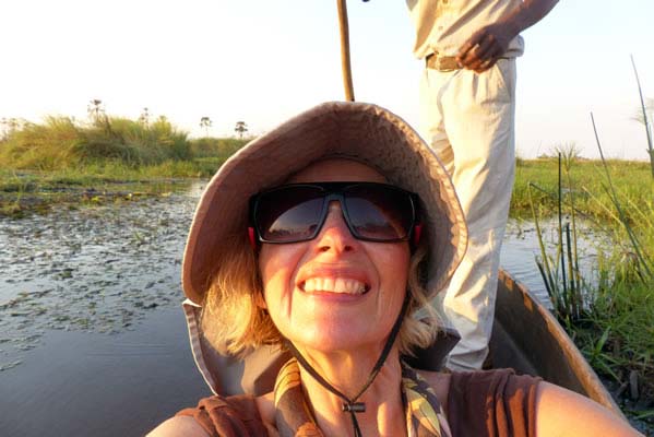 Nancy floating in the boat surrounded by water and tall green grass.