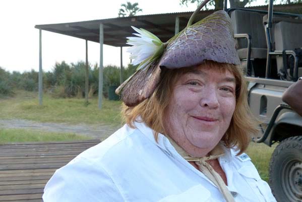 A guest at Tubu Tree wearing a lily pad hat while standing in front of the dark green camp jeep.