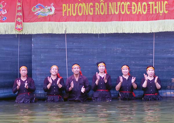 Villagers wading in a pond to present the puppet show.