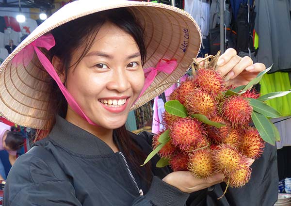 A market guide holding a bunch of ramboutan fruit.